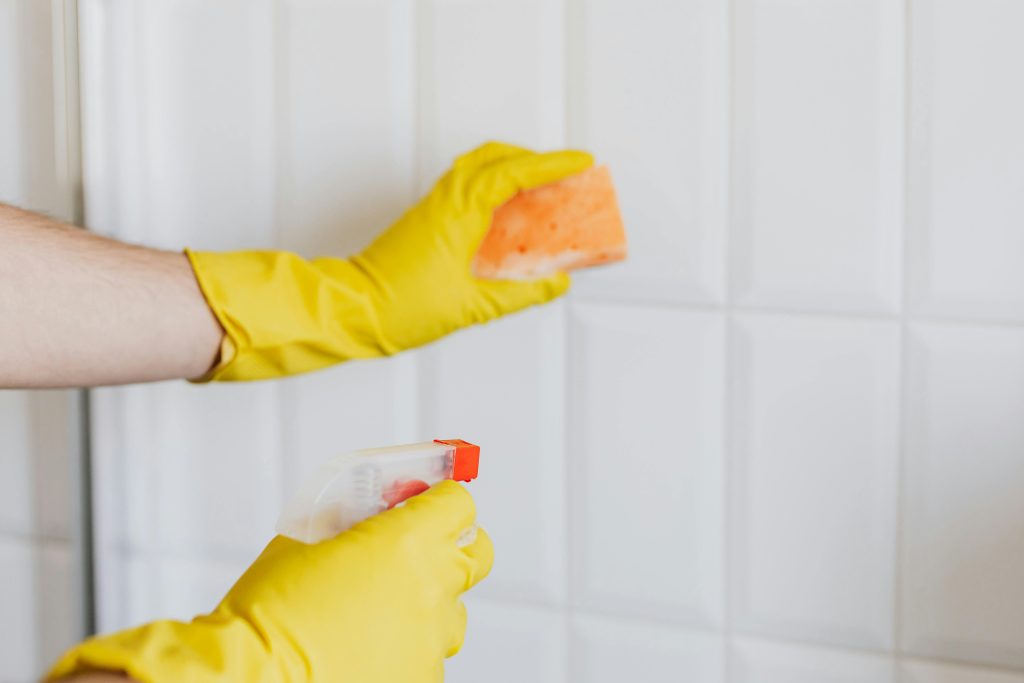 gloved hands cleaning tiles